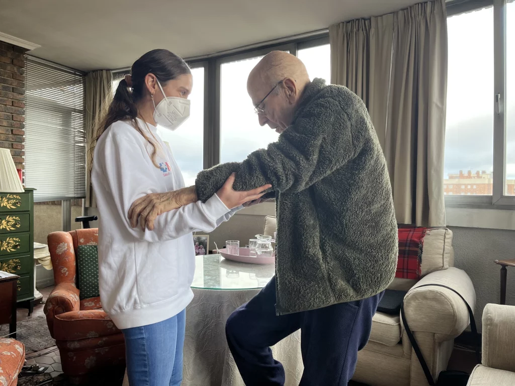 adulto mayor realizando ejercicios de fisioterapia geriátrica con la yuda de fisioterapeuta en Coslada