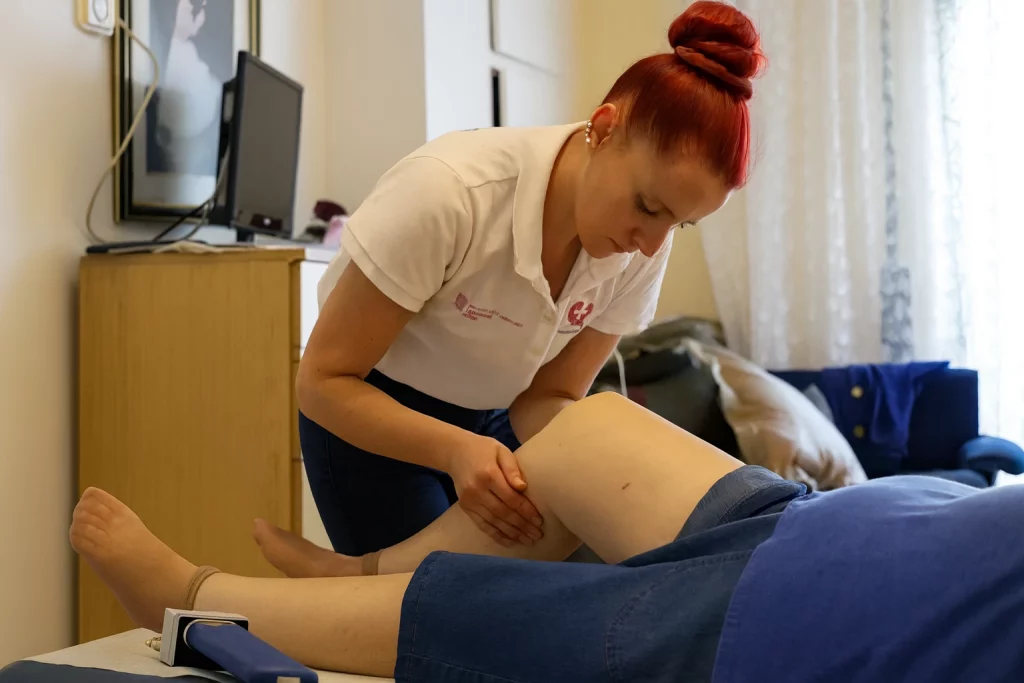 Fisioterapeuta palicando masaje para aliviar dolor de artrosis de rodilla en mujer mayor